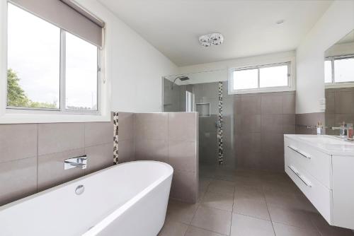 a white bathroom with a tub and a sink at Ellenora in Warrnambool