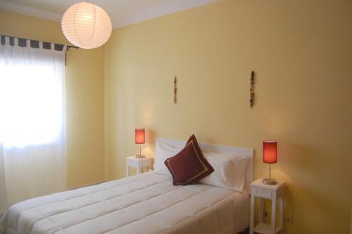 a bedroom with a white bed with two lamps on tables at Flat Via Torraltinha in Lagos