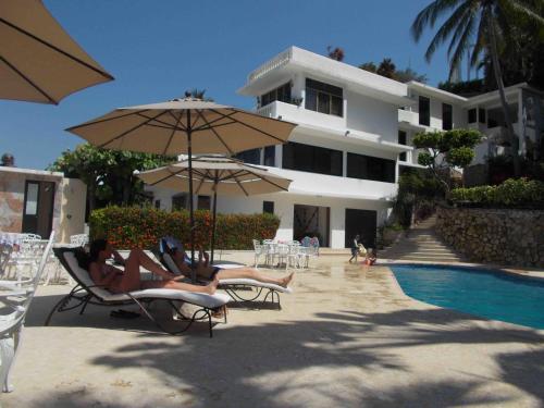 two people laying in chairs under an umbrella near a pool at Penthouse VLM Gran Terraza 200 metros vista inmejorable piscina gigante in Acapulco