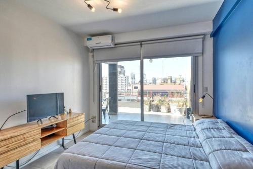 1 dormitorio con 1 cama grande, escritorio y TV en Rent Cramer en Buenos Aires