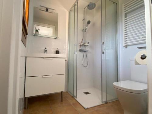 a white bathroom with a shower and a toilet at Allotjament Cal Bru in Sant Llorenç de Morunys