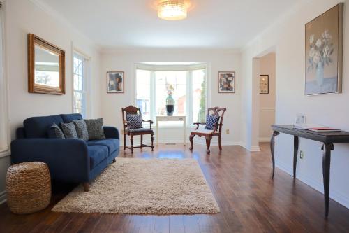 ein Wohnzimmer mit einem blauen Sofa und einem Tisch in der Unterkunft The Promenade Cottage License # 002-2023 in Niagara on the Lake