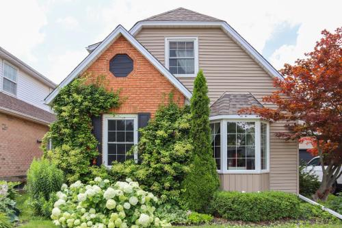 a house with bushes and flowers in front of it at The Promenade Cottage License # 002-2023 in Niagara on the Lake