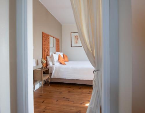 een slaapkamer met een wit bed met oranje kussens bij Villa Hortebise in Salies-de-Béarn