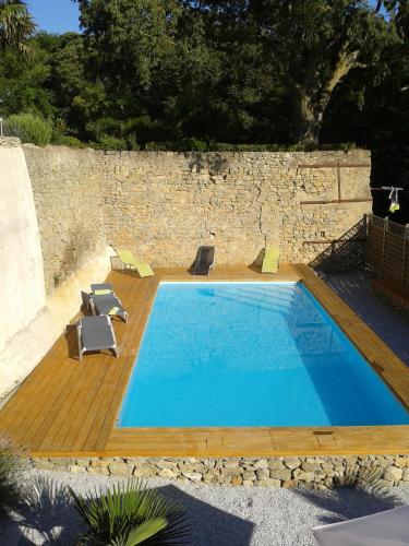a swimming pool with chairs and a stone wall at Logis Hôtel Château De Palaja in Carcassonne