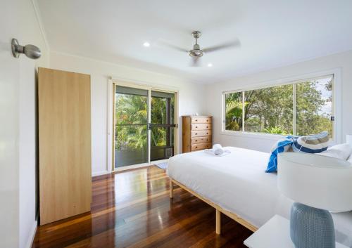 a bedroom with a bed and two windows at Four Beaches-LJHooker Yamba in Yamba