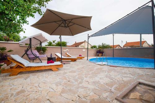 une terrasse avec des chaises et un parasol ainsi qu'une piscine dans l'établissement Spacious apartments with pool, Pakoštane, à Pakoštane