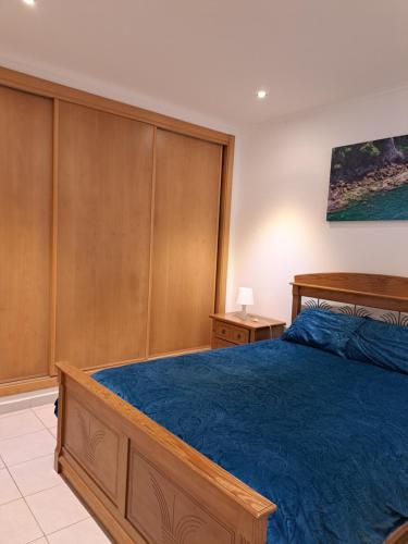 a bedroom with a bed with a blue comforter at Nunes Apartments in Mexilhoeira da Carregacao