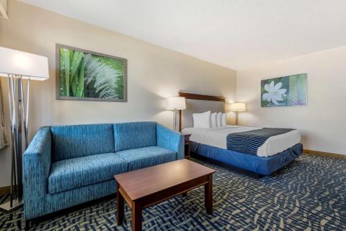 a hotel room with a bed and a blue couch at Best Western Cocoa Beach Hotel & Suites in Cocoa Beach