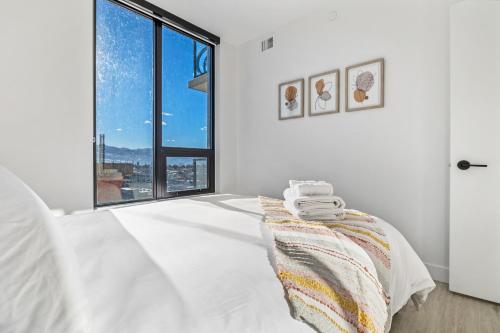 a white bedroom with a bed and a large window at Brand New Luxury Downtown Near the Beach #10 in Kelowna