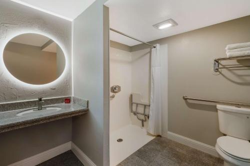 a bathroom with a toilet and a sink and a mirror at Pacific Coast Roadhouse - SureStay Collection by Best Western in San Simeon