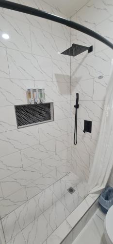 a bathroom with a shower with white tiles at El Rincón in Tunapuna