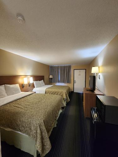 a hotel room with two beds and a flat screen tv at Budget Host Inn in Henderson