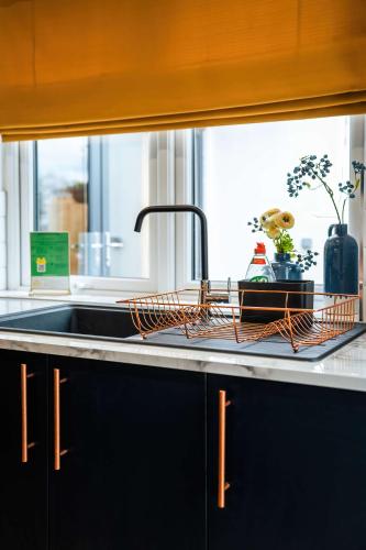 a kitchen sink with a dish drying rack next to a window at Luxury Renovated Bungalow with wheel chair access, Hot Tub and Fire Pit in Wouldham