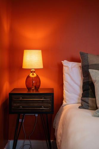 a lamp on a night stand next to a bed at Luxury Renovated Bungalow with wheel chair access, Hot Tub and Fire Pit in Wouldham