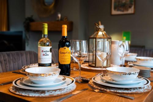a table with two bottles of wine and plates and wine glasses at Luxury Renovated Bungalow with wheel chair access, Hot Tub and Fire Pit in Wouldham