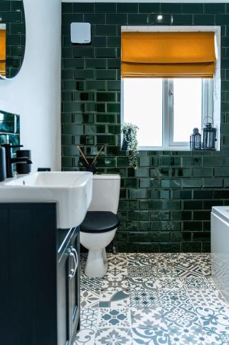 a bathroom with a toilet and a sink and a window at Luxury Renovated Bungalow with wheel chair access, Hot Tub and Fire Pit in Wouldham