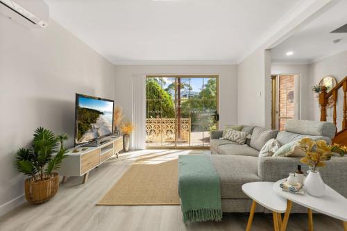 a living room with a couch and a tv at Irrilassa by the Beach by Experience Jervis Bay in Huskisson
