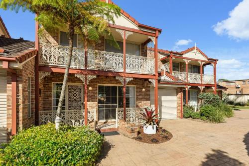 a house with a balcony and palm trees at Irrilassa by the Beach by Experience Jervis Bay in Huskisson
