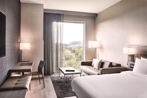 ein Hotelzimmer mit einem Bett, einem Sofa und einem Fenster in der Unterkunft AC Hotel by Marriott Nashville Brentwood in Brentwood