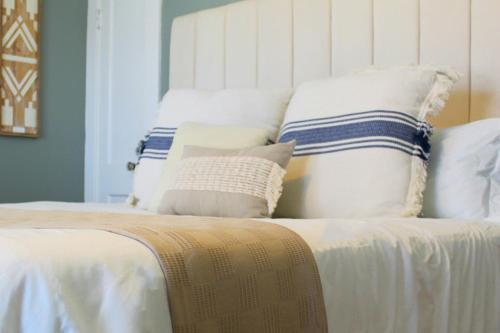 a bed with white and blue pillows on it at Historic Revival 2BR Midtown Memphis Free Parking Fast Wifi Free Parking Yes Pets in Memphis