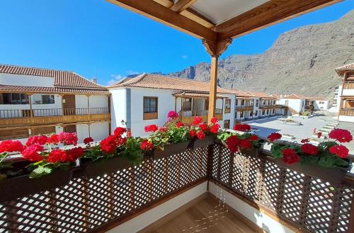 d'un balcon avec des fleurs rouges et des montagnes en arrière-plan. dans l'établissement BuenaVista Gigantes Marina, à Acantilado de los Gigantes