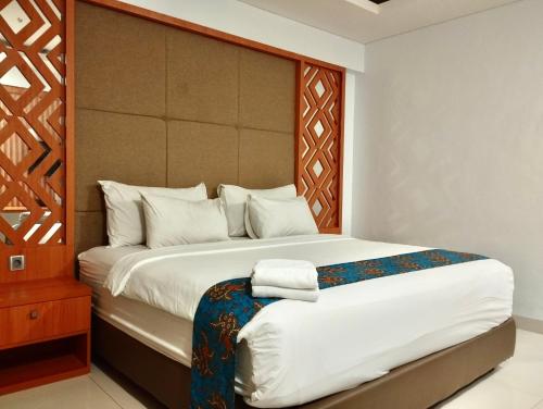 Schlafzimmer mit einem großen Bett mit einem Kopfteil aus Holz in der Unterkunft Lombok Vaganza Hotel in Mataram
