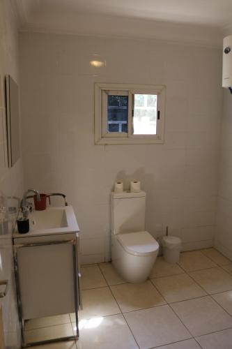 a bathroom with a toilet and a sink and a window at The Rink Apartment's in Sukuta