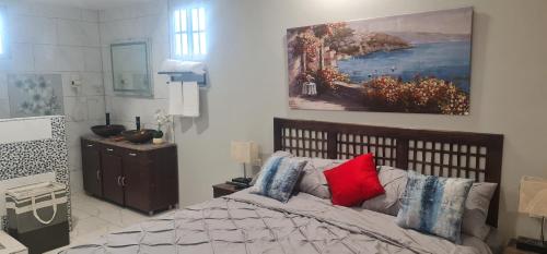 a bedroom with a bed and a painting on the wall at El Rincón in Tunapuna