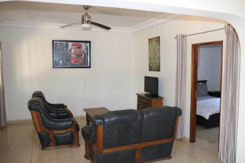 a living room with a couch and a television and a bed at The Rink Apartment's in Sukuta