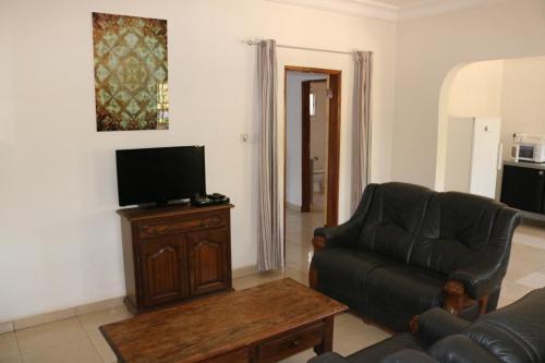a living room with a couch and a flat screen tv at The Rink Apartment's in Sukuta