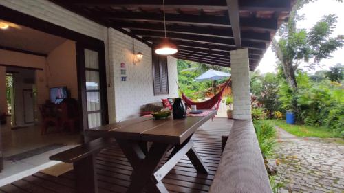 a wooden deck with a table and a hammock at Casa da Baía in Angra dos Reis