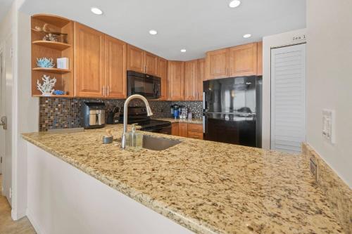 a kitchen with a granite counter top and wooden cabinets at Sapphire Oasis- Heavenly Ocean View and Resort in Kahana