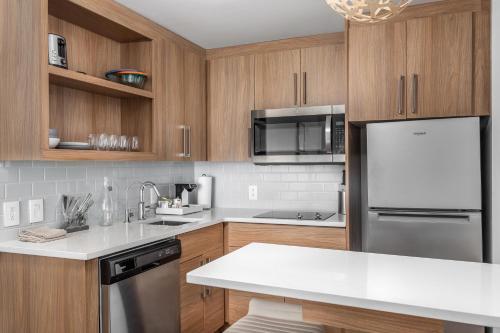 a kitchen with wooden cabinets and a stainless steel refrigerator at Element Knoxville West in Knoxville