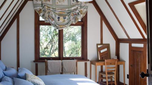 Un dormitorio con una cama y una ventana con una lámpara de araña. en Rush Cottage en Havelock North