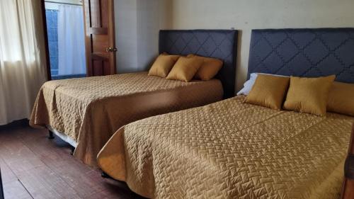 duas camas sentadas uma ao lado da outra num quarto em AZURA HOTEL BOUTIQUE em Cobán