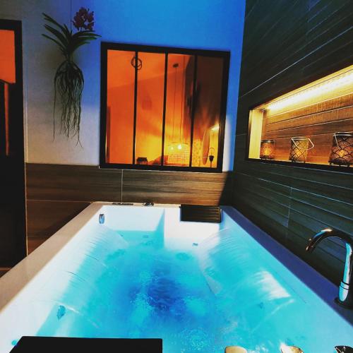 La salle de bains est pourvue d'une grande baignoire et d'une fenêtre. dans l'établissement SAUNA, BALNEO, TERRASSE, PARKING, Le tout totalement privé dans maison indépendante à la décoration soignée, ensoleillé et sans vis à vis, Prise VE, Calme et discrétion Garantis, Idéalement situé pour visiter la région, Animaux bienvenues, à Saint-Jean-de-la-Neuville