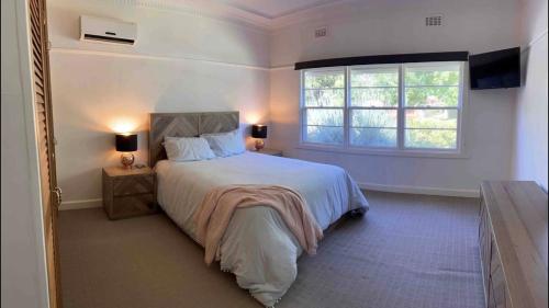 a bedroom with a large bed and a window at Cheerful 3 bedroom home in the centre of town in Shepparton