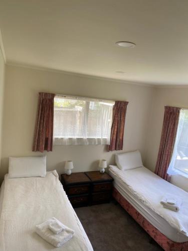 two beds in a room with two windows at The Gardens' Treasure in Auckland