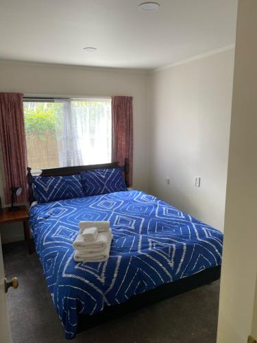 a bedroom with a blue bed with towels on it at The Gardens' Treasure in Auckland