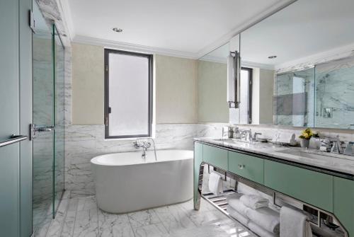 a bathroom with a tub and a sink and a mirror at Loews Regency New York Hotel in New York