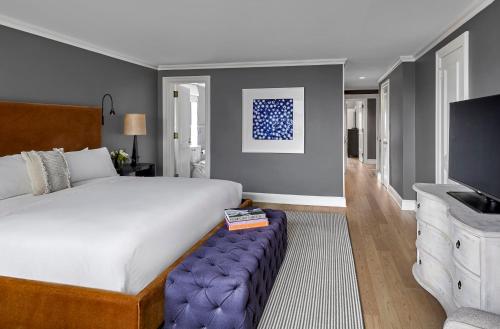 a bedroom with a large bed with a blue ottoman and a television at Loews Regency New York Hotel in New York