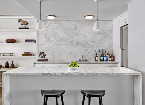 a kitchen with a white counter with two stools at Loews Regency New York Hotel in New York