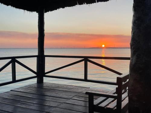 a sunset over the ocean with a bench on a porch at HOTEL ISLA in Isla Aguada