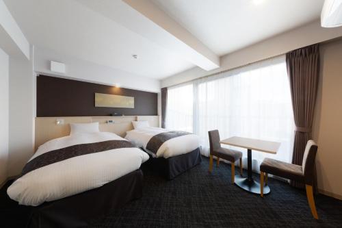 a hotel room with two beds and a table at Hotel GOCO stay Kyoto Shijo Kawaramachi in Kyoto