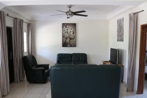 a living room with two chairs and a ceiling fan at The Rink Apartment's in Sukuta