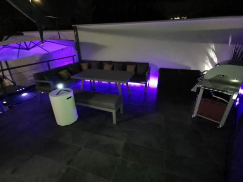 Cette chambre dispose d'un canapé et d'une table avec des lumières violettes. dans l'établissement Maison spa, à Morangis