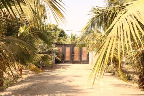 a driveway with palm trees in front of a building at The Rink Apartment's in Sukuta