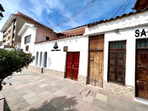 un groupe de bâtiments blancs avec portes rouges dans l'établissement Hostal María Angola, à Cusco