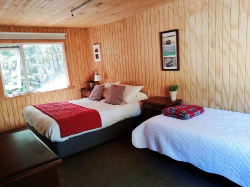 2 camas en una habitación con paneles de madera en Cabaña Fio-Fio Conguillio National Park, en Conguillio